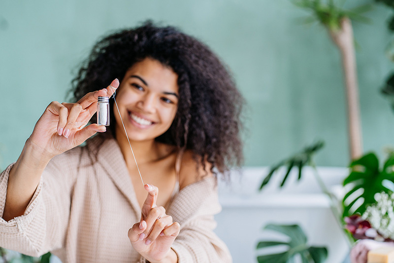 Smiling Woman Holding Out Floss