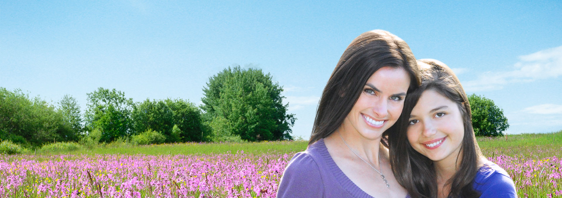 Mother and daughter smiling in a field of flowers.